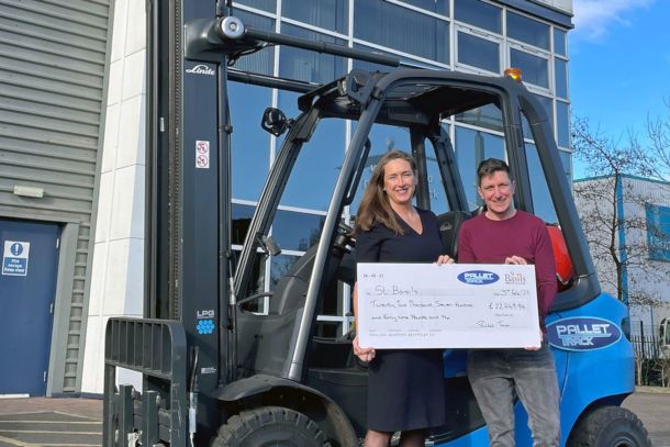 Two People Standing in front of forklift with large cheque